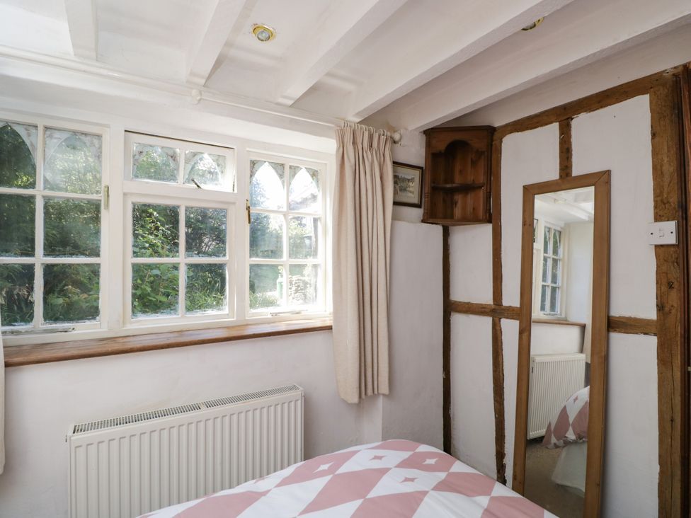 A bedroom with windows and a mirror at Ivy Cottage Woolverton near Beckington