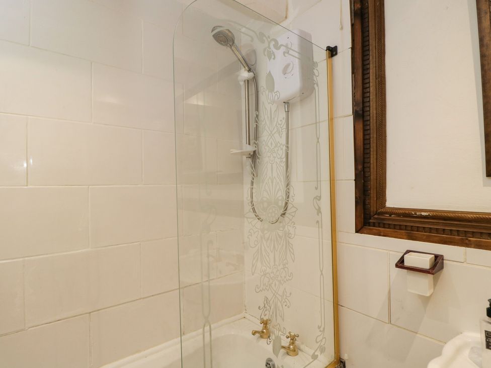 A bathroom with a bathtub and shower at Ivy Cottage in Woolverton near Beckington