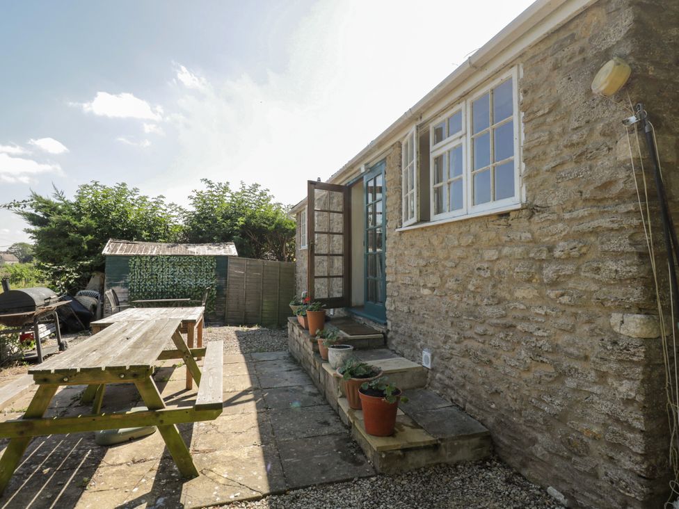 A garden with a table, chairs, and planters at Ivy Cottage in Woolverton near Beckington