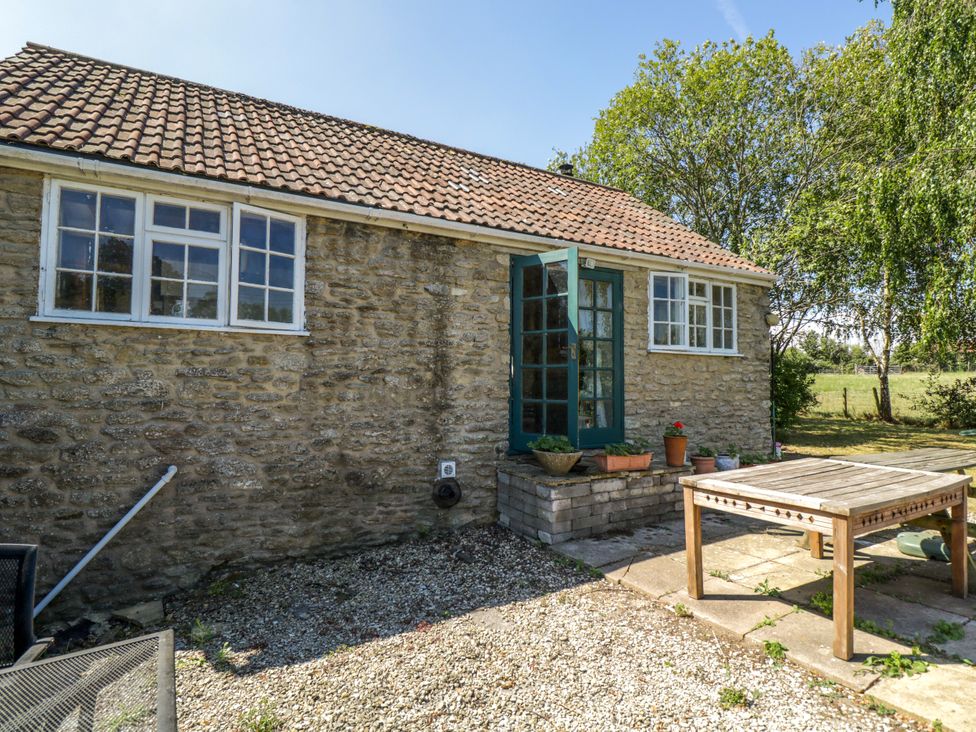 An outdoor area with a stone wall and table at Ivy Cottage in Woolverton near Beckington