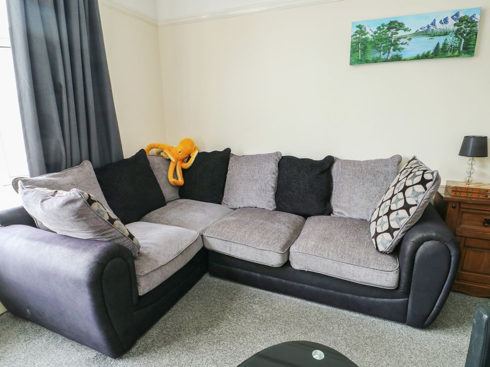 A living room with a sofa and cushions at Sea Breeze in Rhos-on-Sea