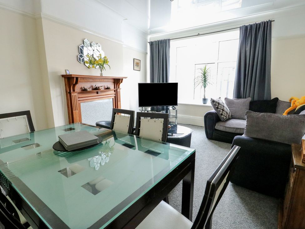 A living room with a dining table and television at Sea Breeze in Rhos-on-Sea