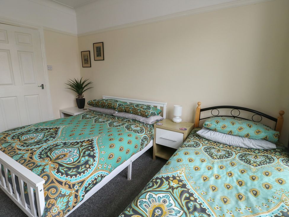A bedroom with two beds and a nightstand at Sea Breeze in Rhos-on-Sea