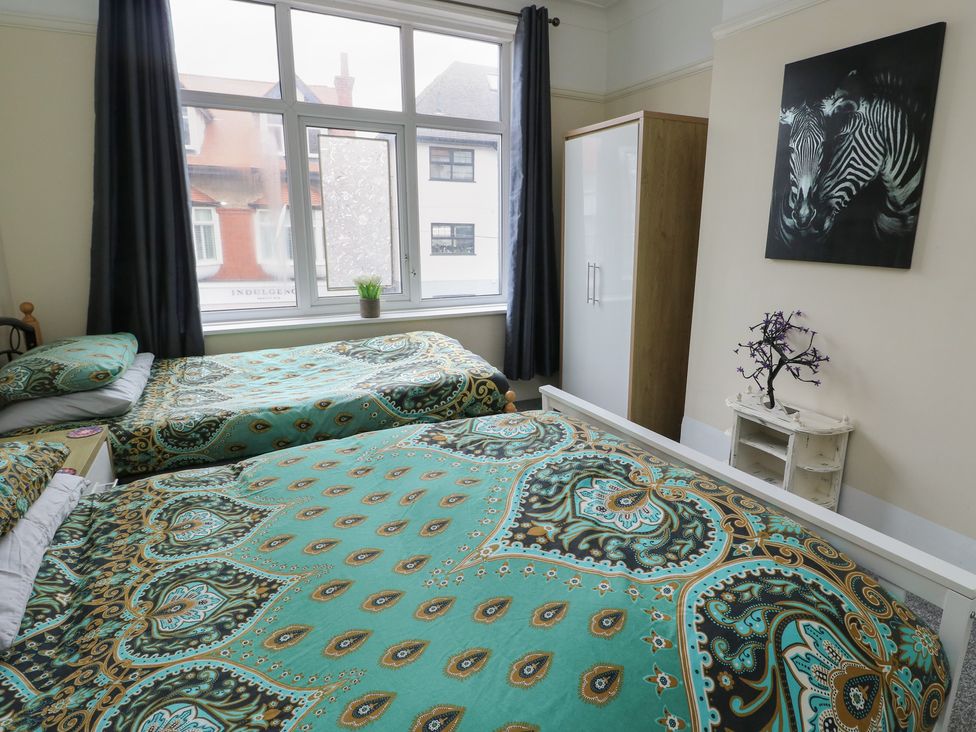 A bedroom with two beds and a wardrobe at Sea Breeze in Rhos-on-Sea