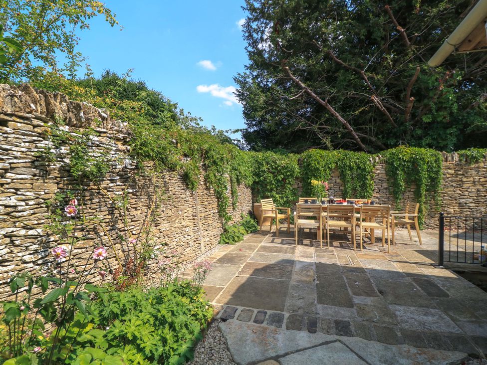 A garden with a stone wall and a dining table at Easter Cottage Burford