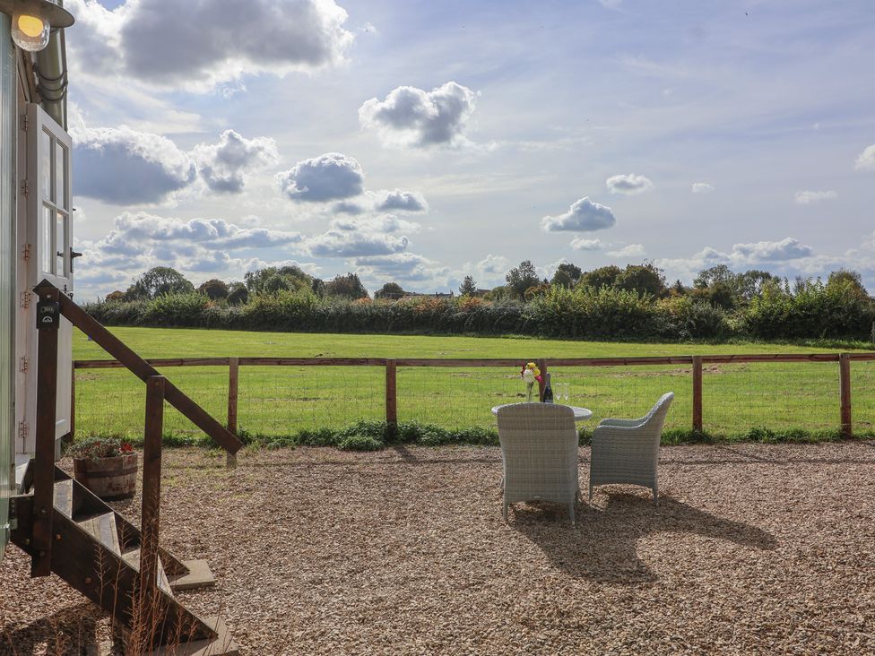 An outdoor seating area with a table and chairs at The Shepherds Hut in Chippenham