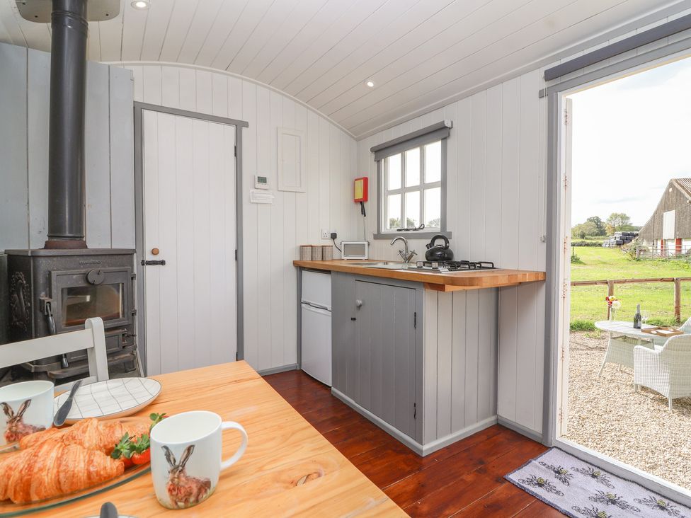 A kitchen with stove and dining table at The Shepherds Hut in Chippenham