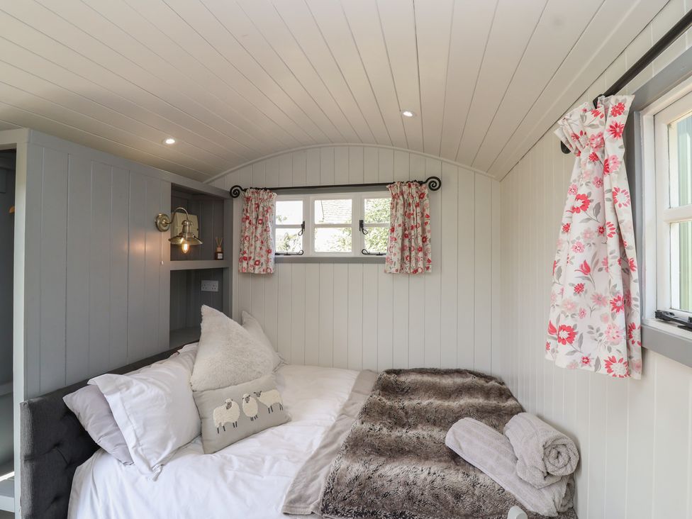 A bedroom with a bed and window at The Shepherds Hut in Chippenham
