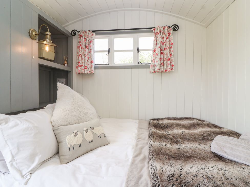 A bedroom with a bed and pillows at The Shepherds Hut in Chippenham