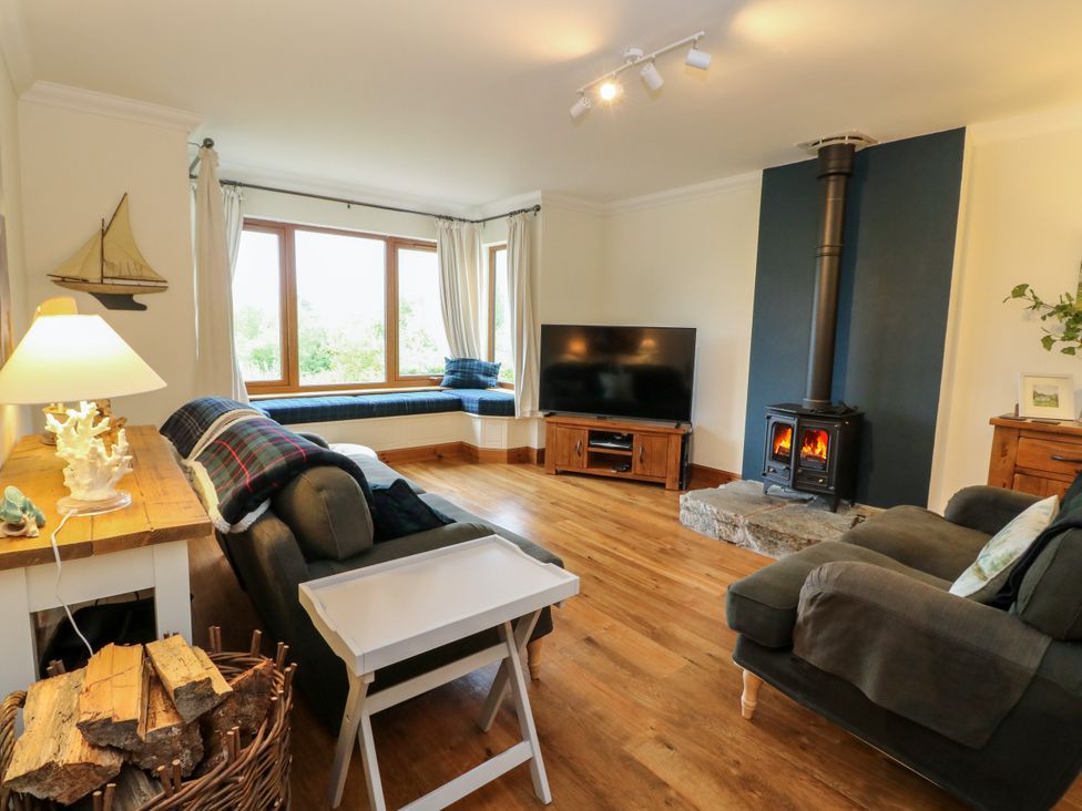 A living room with a television and a wood stove at Thistle Do Lochailort