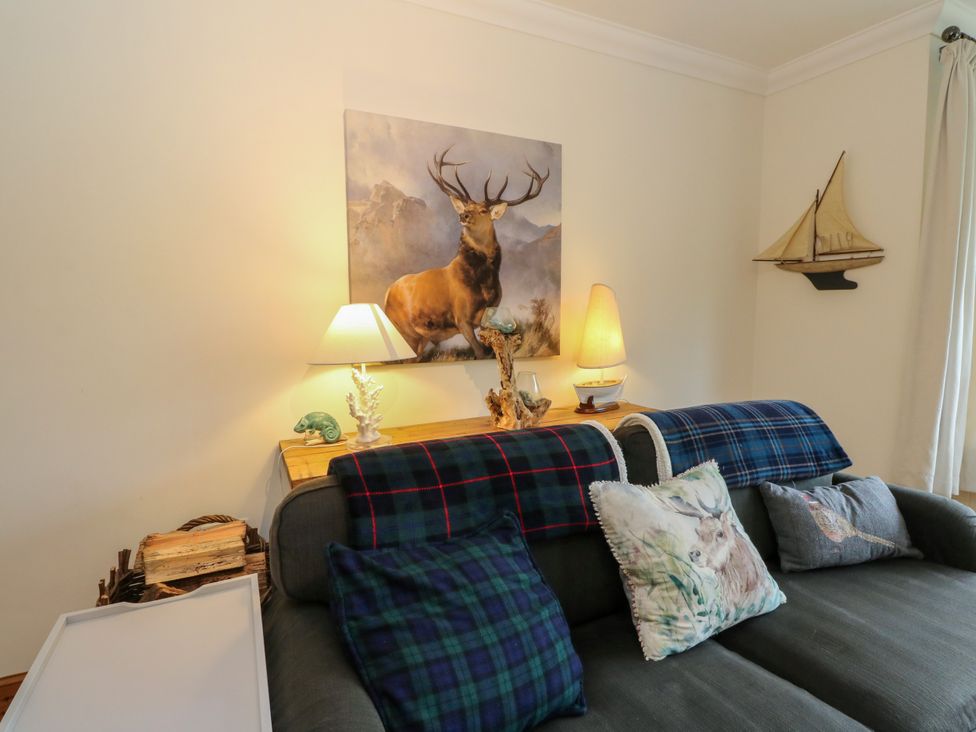 A living room with a sofa and decorative items at Thistle Do in Lochailort