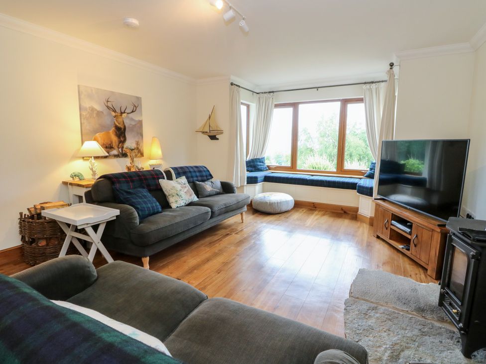 A living room with a sofa and television at Thistle Do in Lochailort