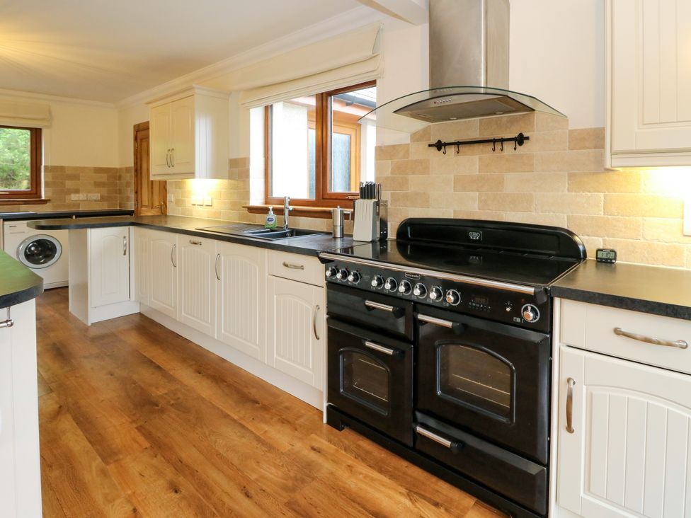 A kitchen with a black oven and a washing machine at Thistle Do Lochailort