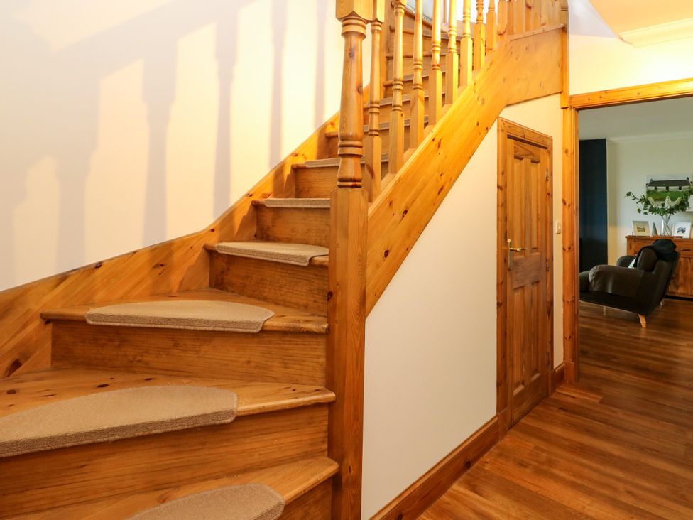 A staircase with wooden railing and door in a hallway at Thistle Do Lochailort