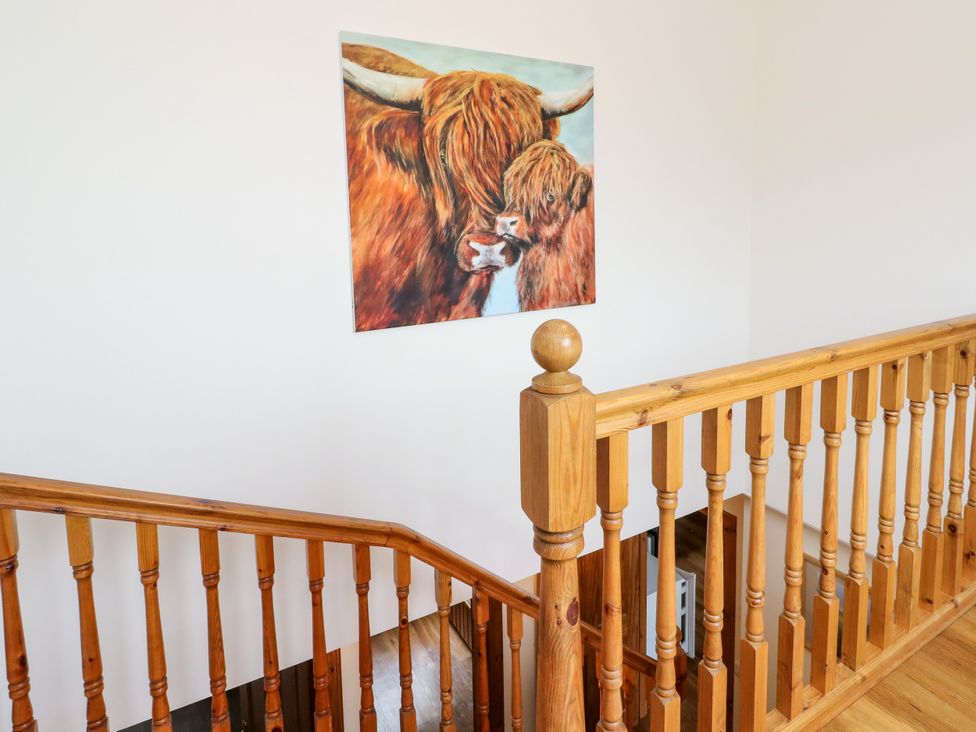 A staircase with a wooden railing and a painting at Thistle Do in Lochailort