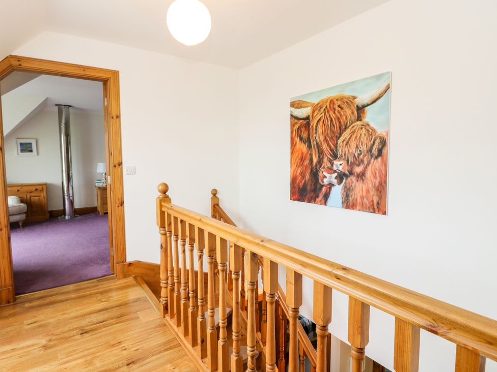 A hallway with a painting and wooden railing at Thistle Do in Lochailort