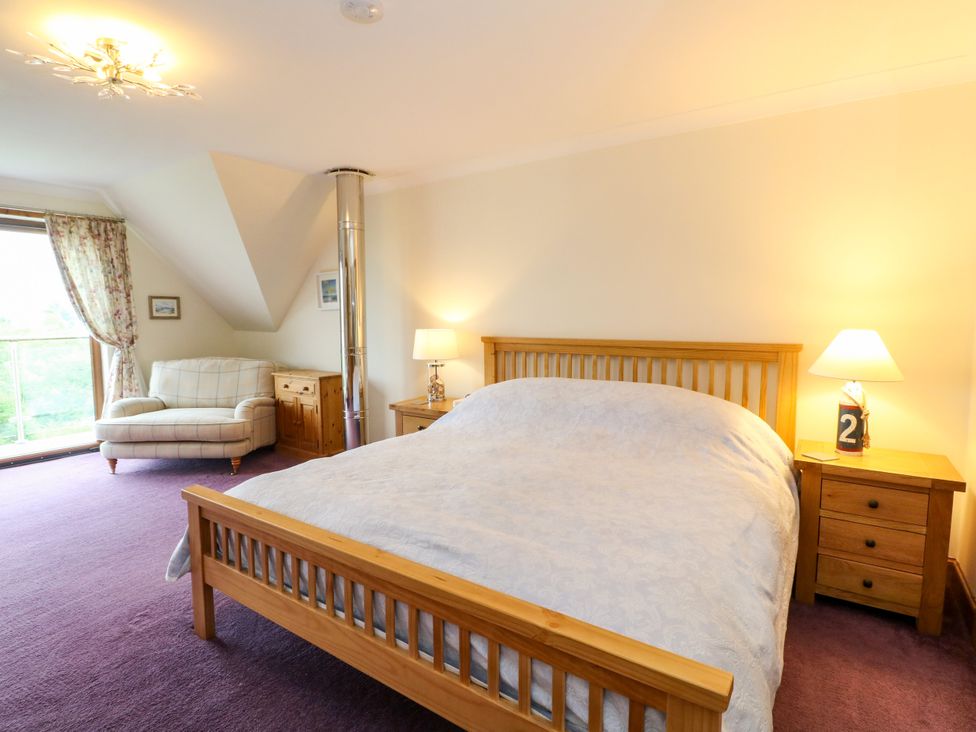 A bedroom with a bed and armchair at Thistle Do in Lochailort