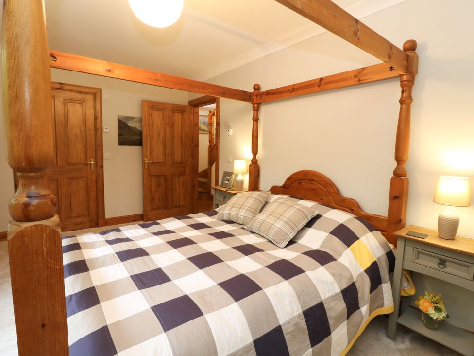 A bedroom with a four-poster bed and nightstand at Thistle Do in Lochailort