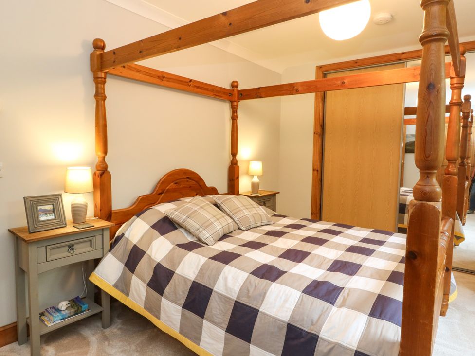 A bedroom with a four-poster bed and bedside table at Thistle Do in Lochailort