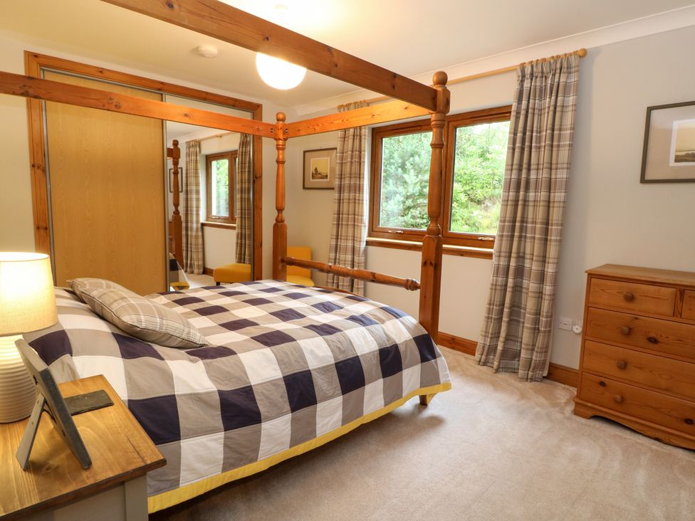 A bedroom with a bed and windows at Thistle Do in Lochailort