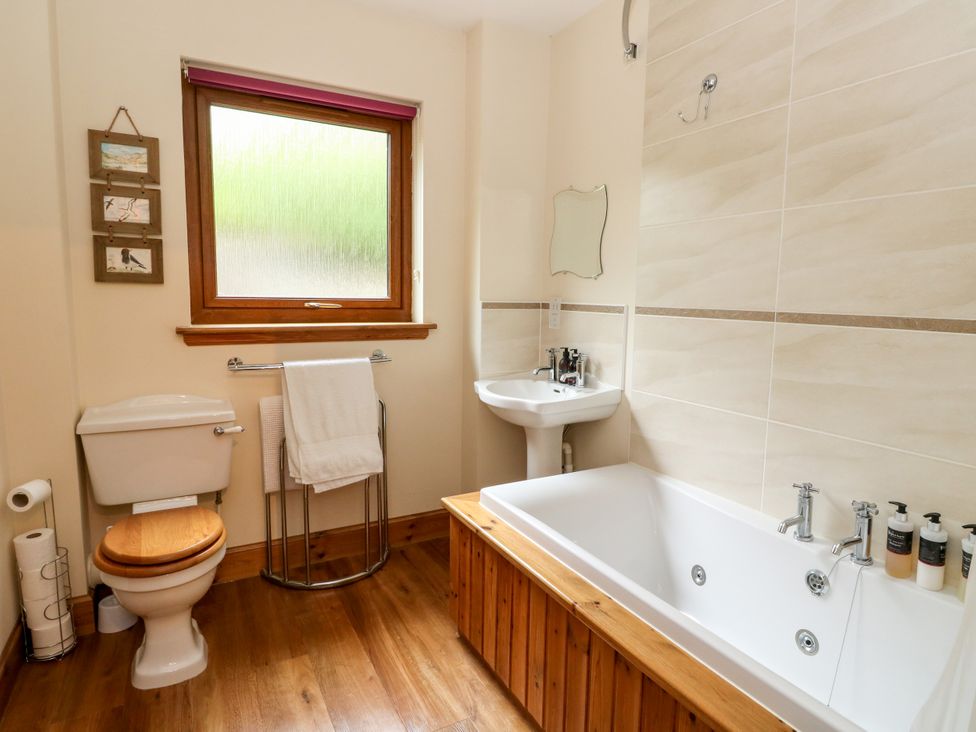 A bathroom with a bathtub, toilet, and sink at Thistle Do, Lochailort