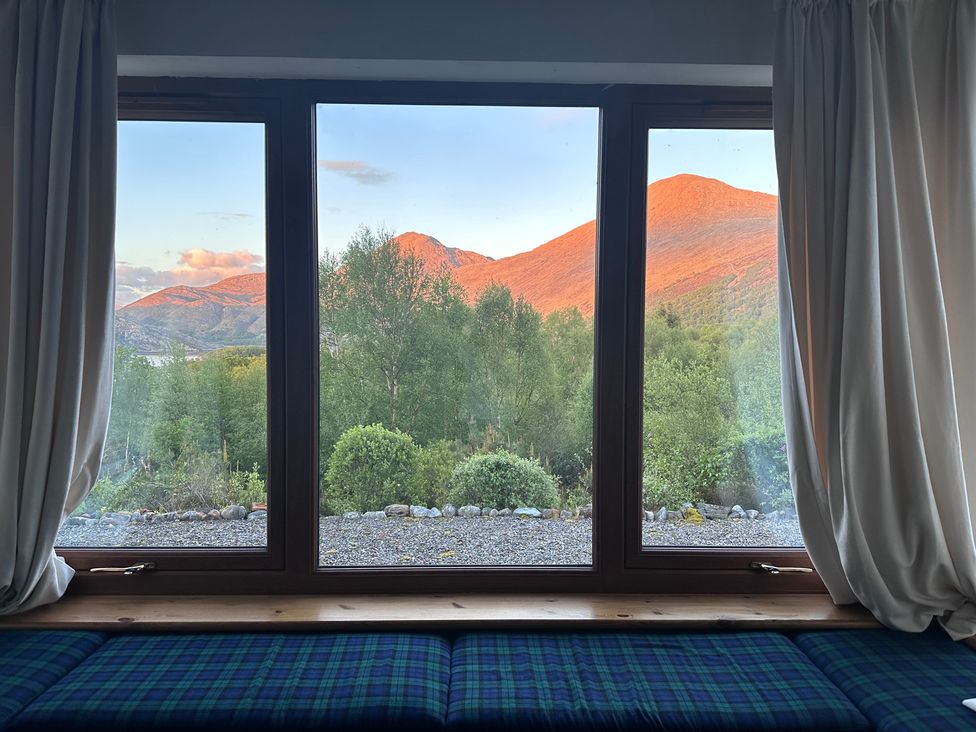 A window view of mountains and trees at Thistle Do in Lochailort
