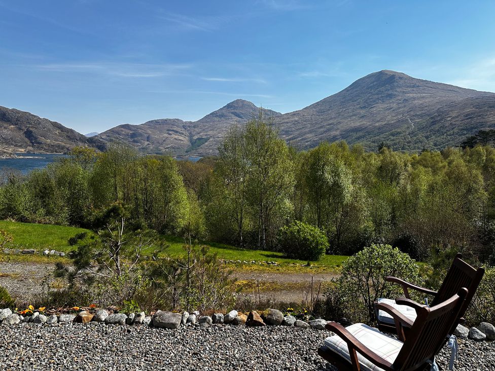 A view of mountains and trees with gravel and chairs at Thistle Do Lochailort