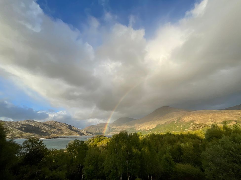 A scenic view of mountains and water with a rainbow at Thistle Do Lochailort