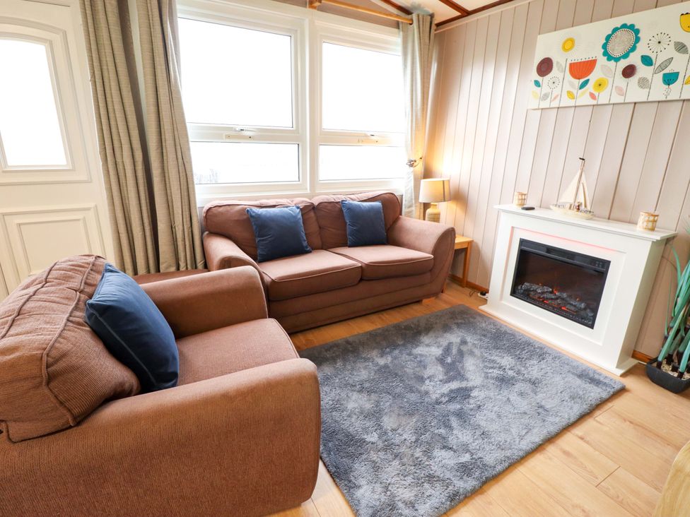 A living room with a sofa and fireplace at Moggs Retreat in Chapel St Leonards