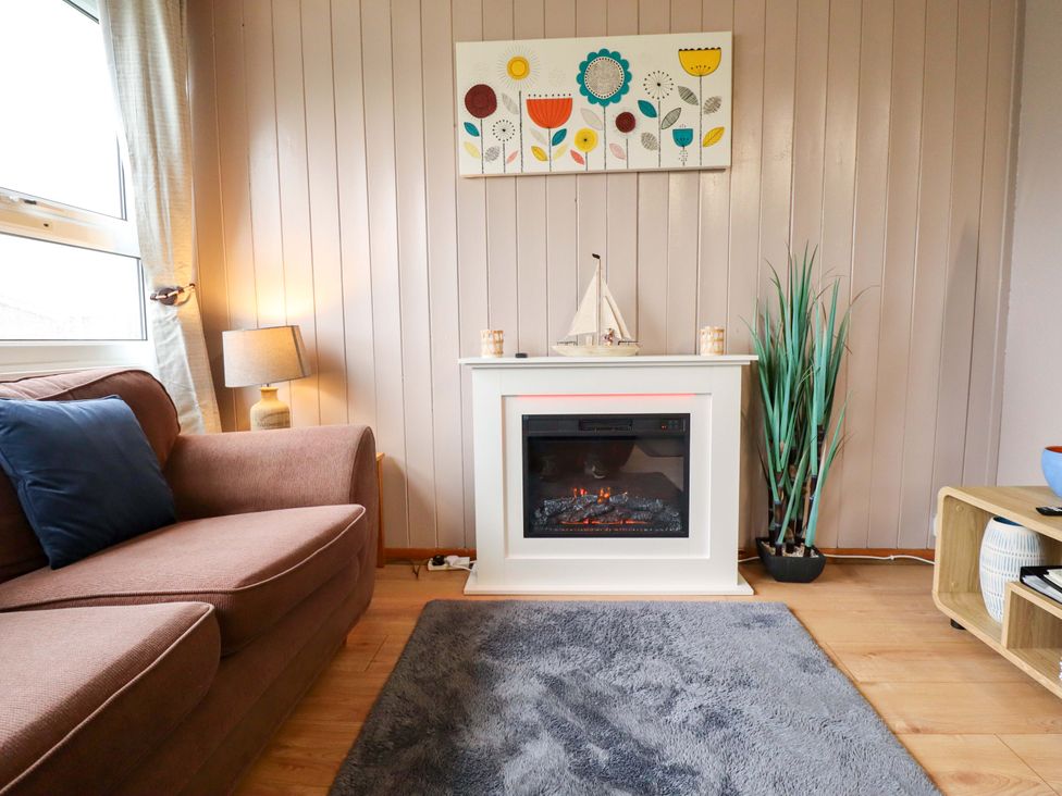 A living room with a sofa and fireplace at Moggs Retreat in Chapel St Leonards