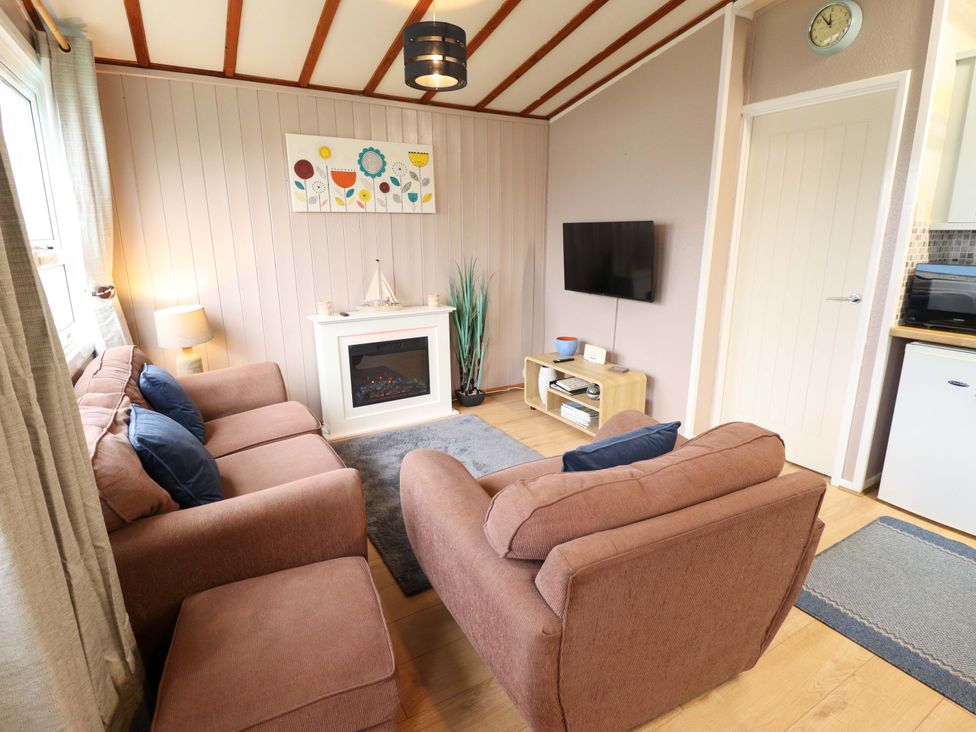 A living room with a couch and television at Moggs Retreat in Chapel St Leonards