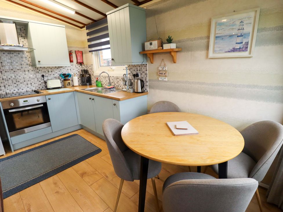 A kitchen with a table and chairs at Moggs Retreat in Chapel St Leonards