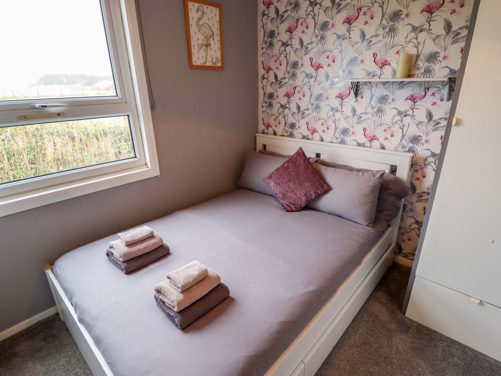 A bedroom with a bed and window at Moggs Retreat in Chapel St Leonards