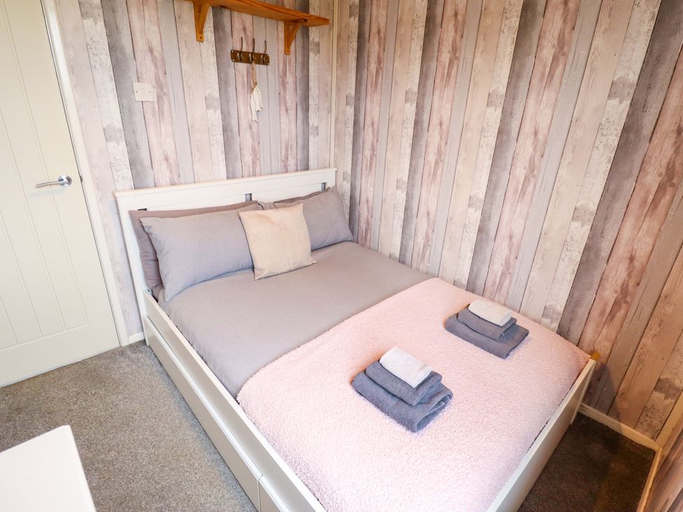 A bedroom with a bed and towels arranged on top at Moggs Retreat Chapel St Leonards