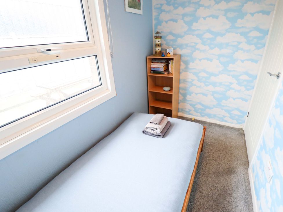 A bedroom with a bed and bookshelf at Moggs Retreat in Chapel St Leonards