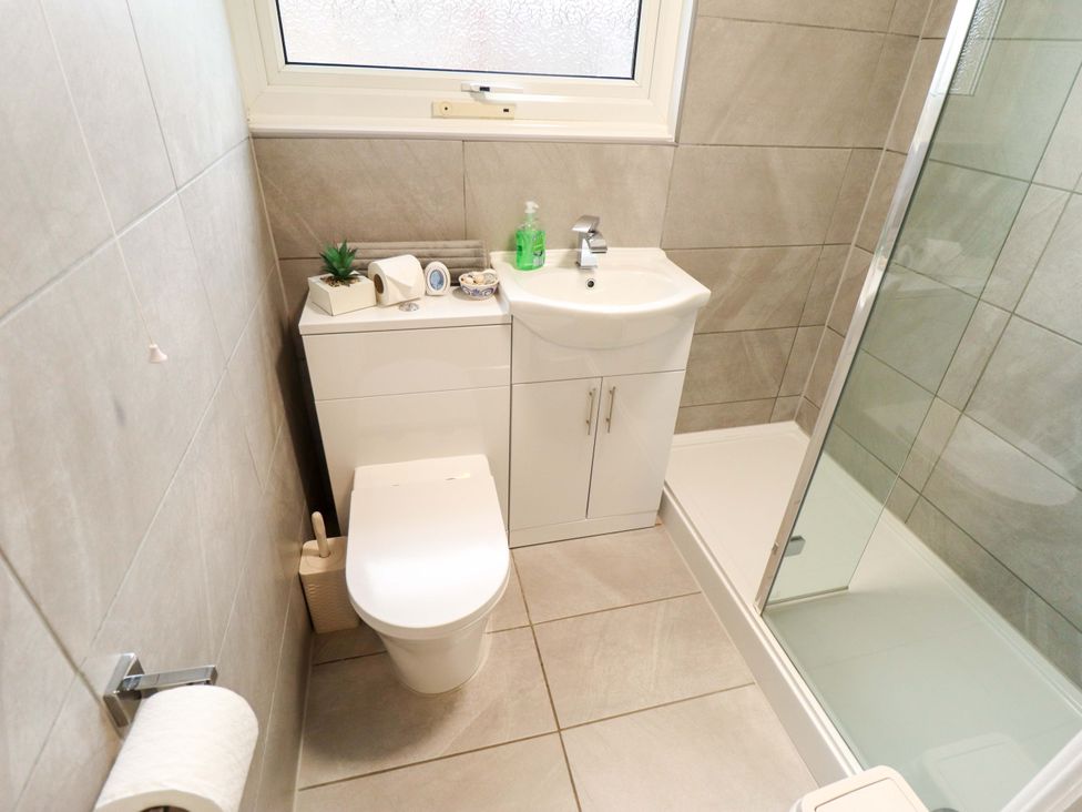 A bathroom with a shower, toilet, and sink at Moggs Retreat in Chapel St Leonards