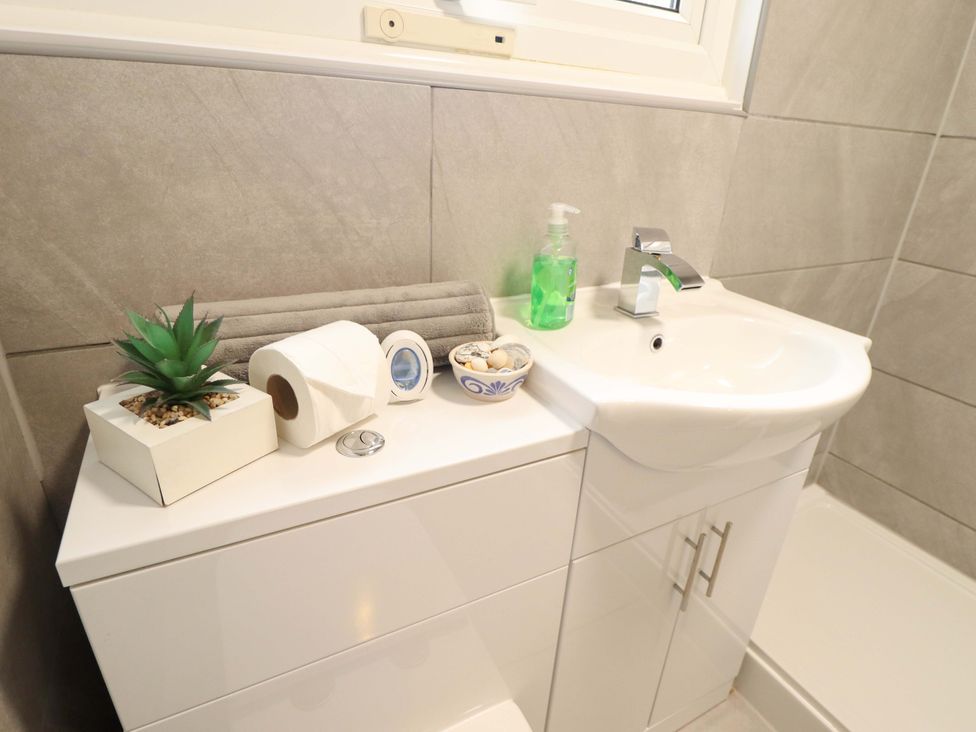 A sink with a soap dispenser and decorative items at Moggs Retreat in Chapel St Leonards