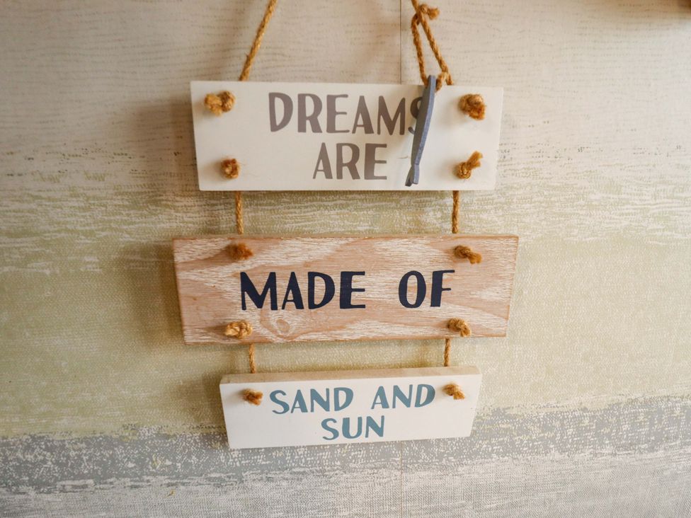 A wooden sign with the text 'DREAMS ARE MADE OF SAND AND SUN' at Moggs Retreat in Chapel St Leonards