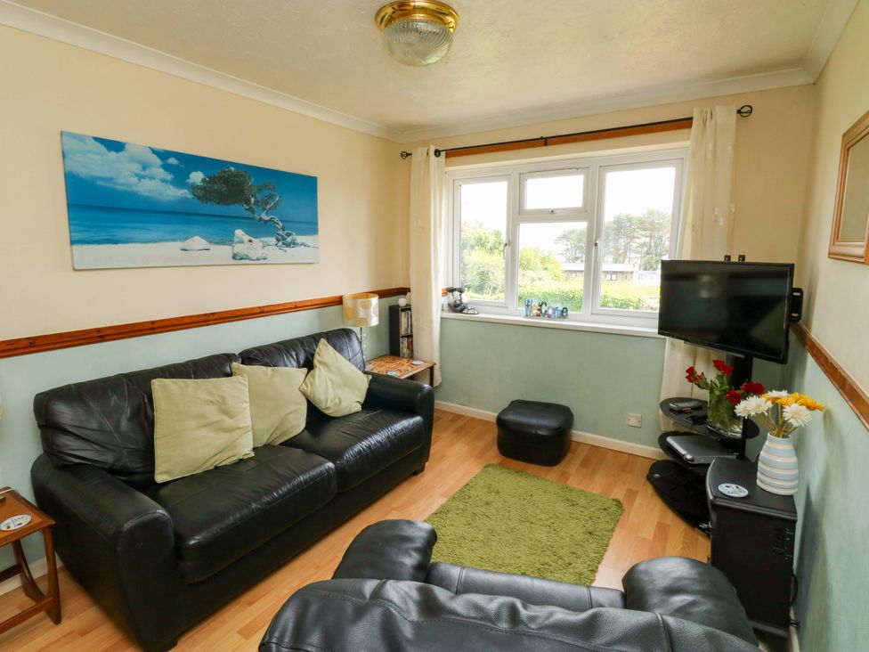 A living room with a sofa, television, and window at Cottage 28 in Brixham