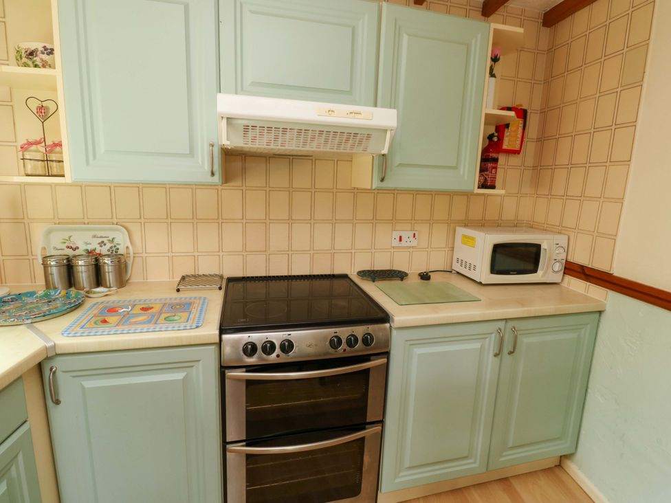 A kitchen with stove, oven, microwave, and cabinets at Cottage 28 in Brixham