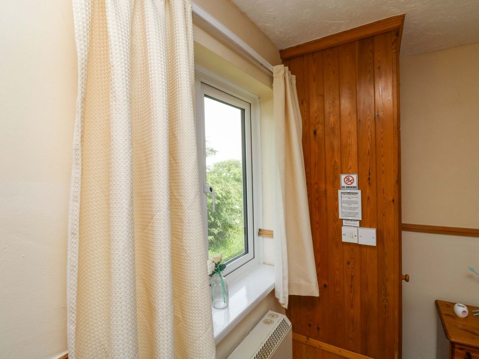 A bedroom with a window and curtains at Cottage 28 in Brixham