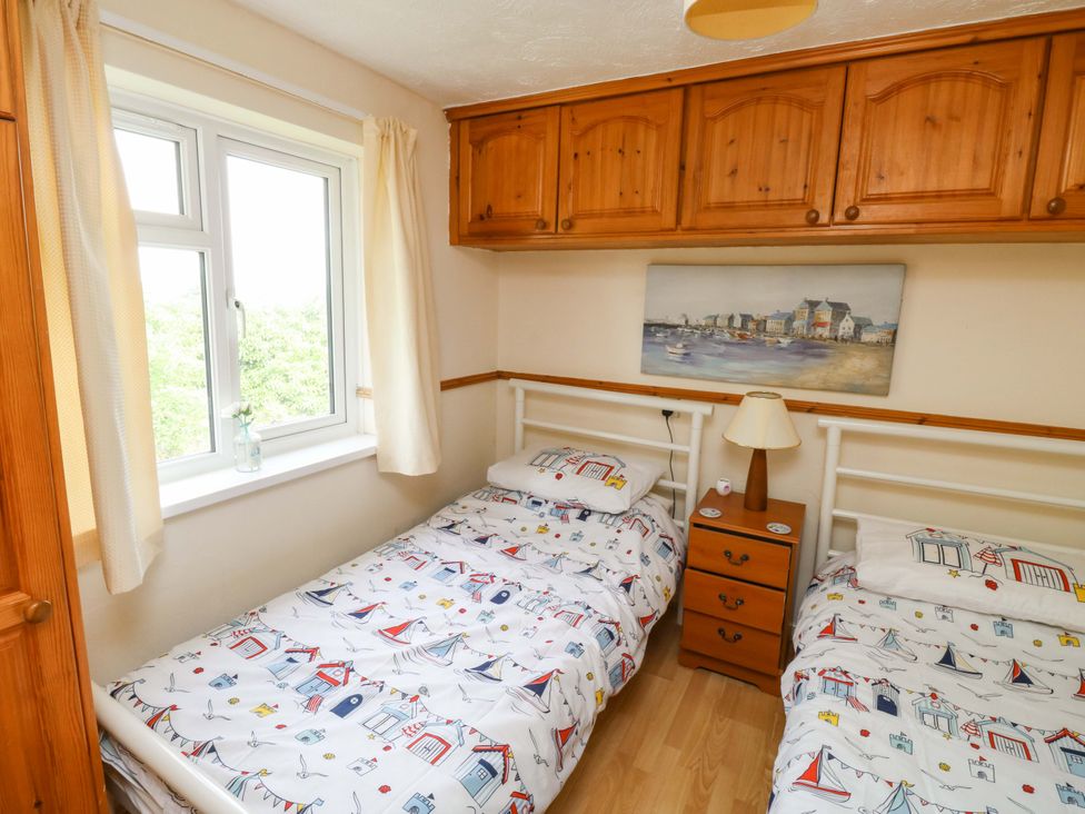 A bedroom with two beds and a window at Cottage 28 in Brixham