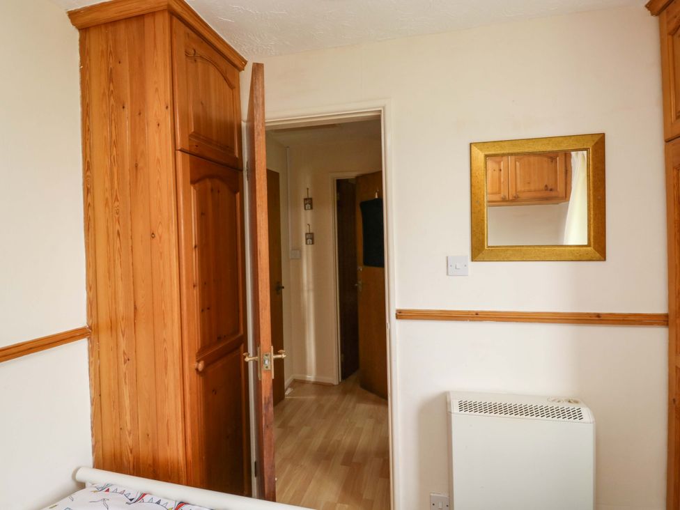 A bedroom with a mirror and wardrobe at Cottage 28 in Brixham
