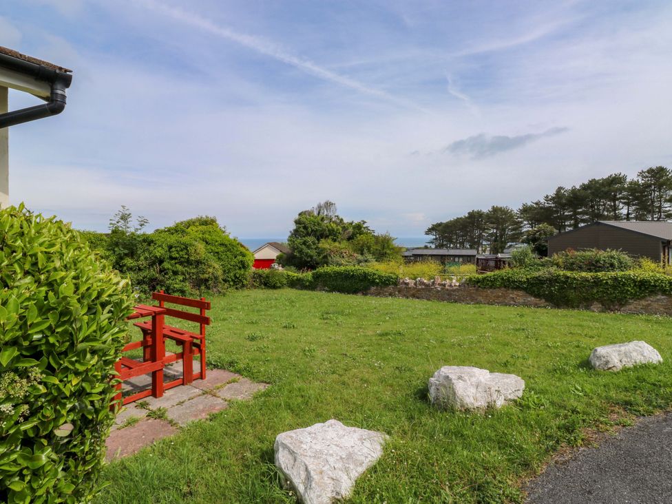 A garden with a red bench and green grass at Cottage 28 in Brixham