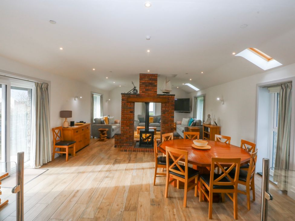 A living room with a fireplace and dining table at Bwthyn Alberts Trearddur Bay