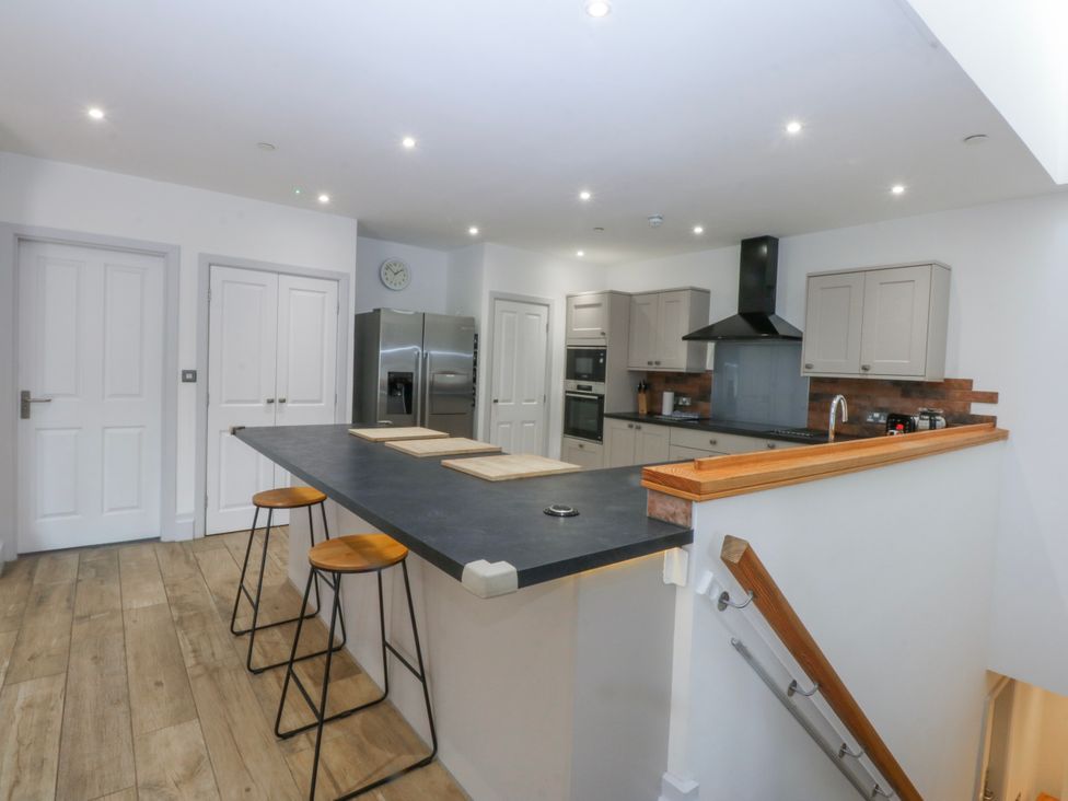 A kitchen with a counter and stools at Bwthyn Alberts Trearddur Bay