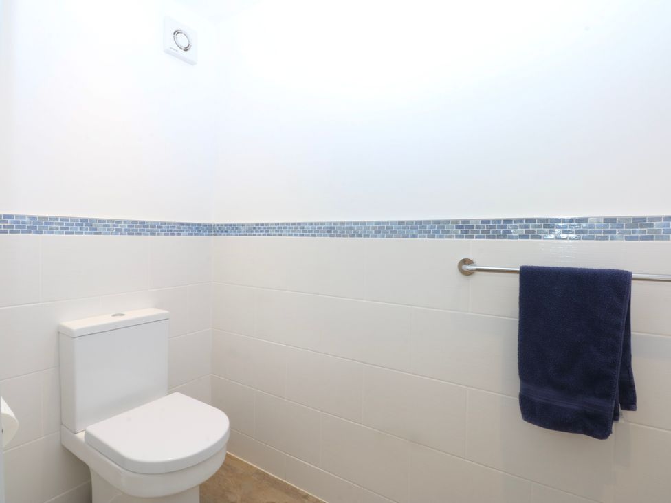 A bathroom with a toilet, towel rack and a blue towel at Bwthyn Alberts, Trearddur Bay