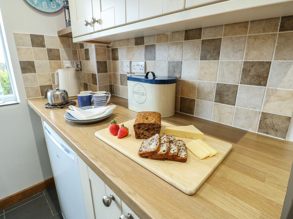 A kitchen with bread and cheese on a cutting board at Yr Orsedd in Llanfaethlu