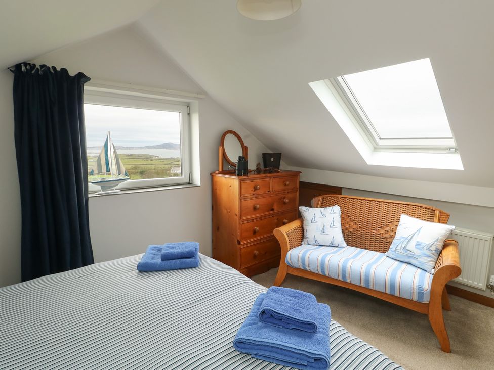 A bedroom with a bed and a sofa at Yr Orsedd in Llanfaethlu