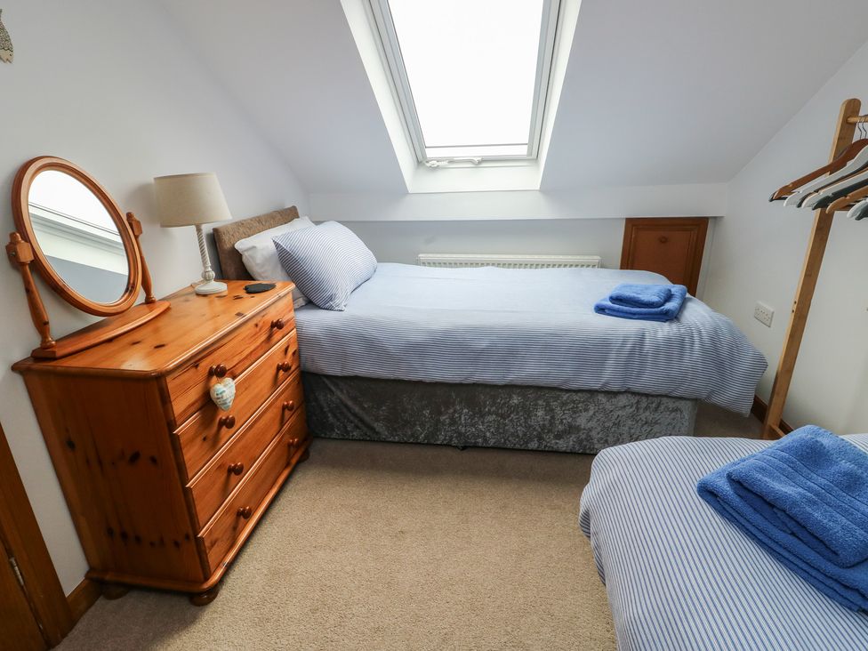 A bedroom with a bed, dresser, and mirror at Yr Orsedd in Llanfaethlu